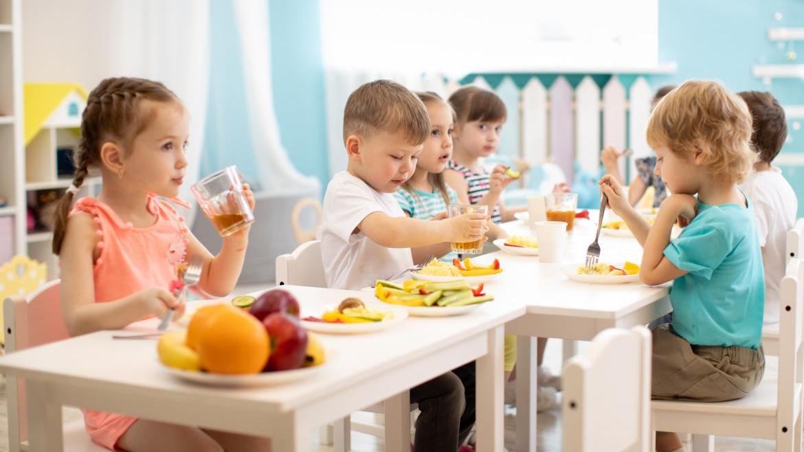 Kinder aus der Kita frühstücken gemeinsam an einem Tisch