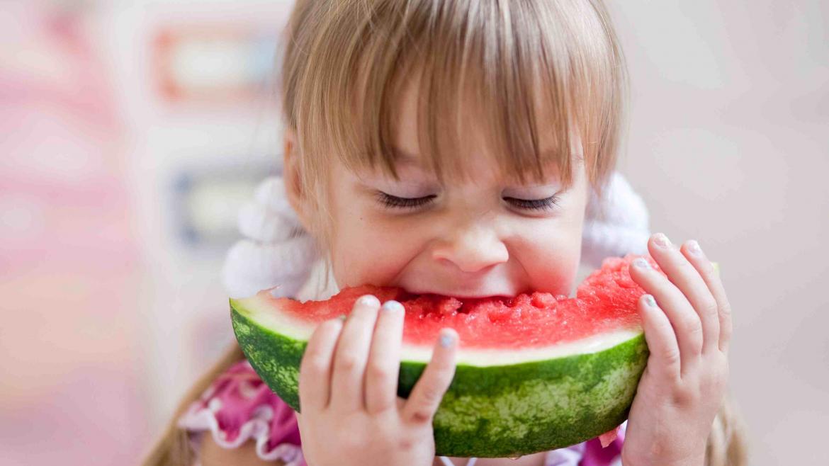 Mädchen beißt voller Genuß in ein Stück Wassermelone