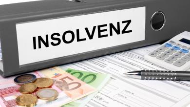 Insolvenzordner grau mit Taschenrechner, Stift und Geld