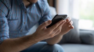 Mann auf Sofa mit Smartphone in der Hand