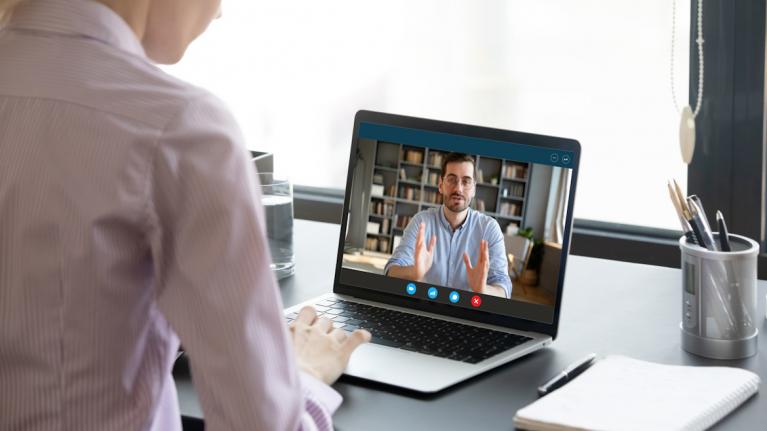 Videokonferenz mit einem Laptop, Blick über Schulter einer Frau zu Onlinecoaching Kostenfalle