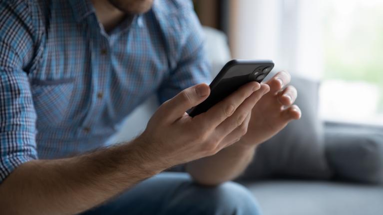 Mann auf Sofa mit Smartphone in der Hand