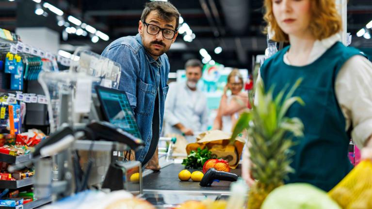 Mann an der Supermarktkasse wundert sich über den Preis