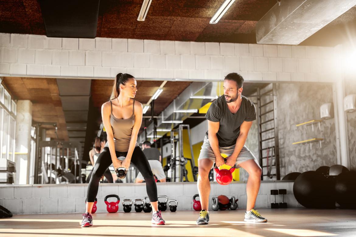 Mann und Frau mit Gewichten in Fitnessraum