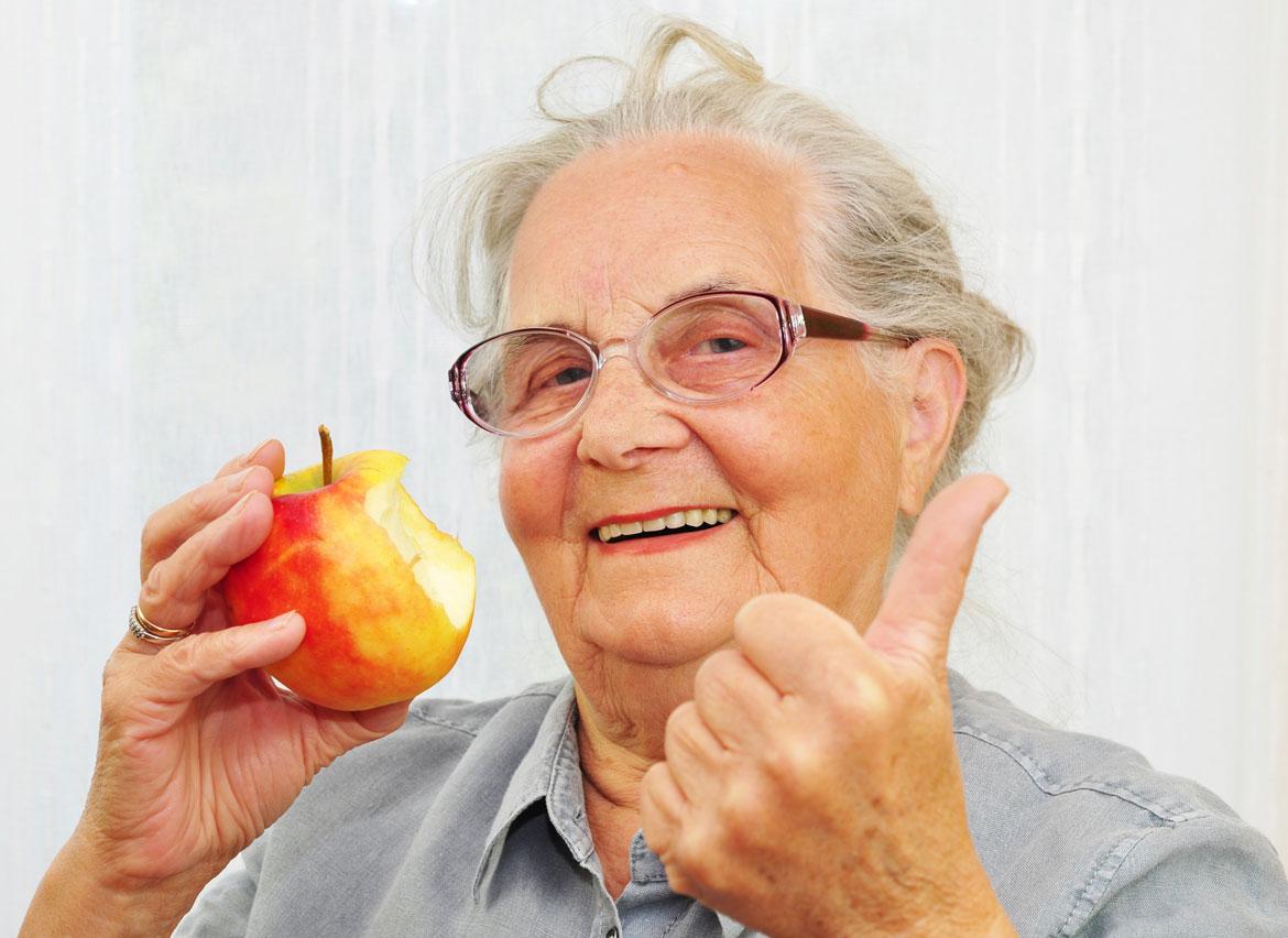 Ältere Dame mit Apfel in der Hand und Daumen hoch zu Artikel: Vortrag gesund älter werden - Mythen um Lebensmittel, hätten Sie es gewusst.