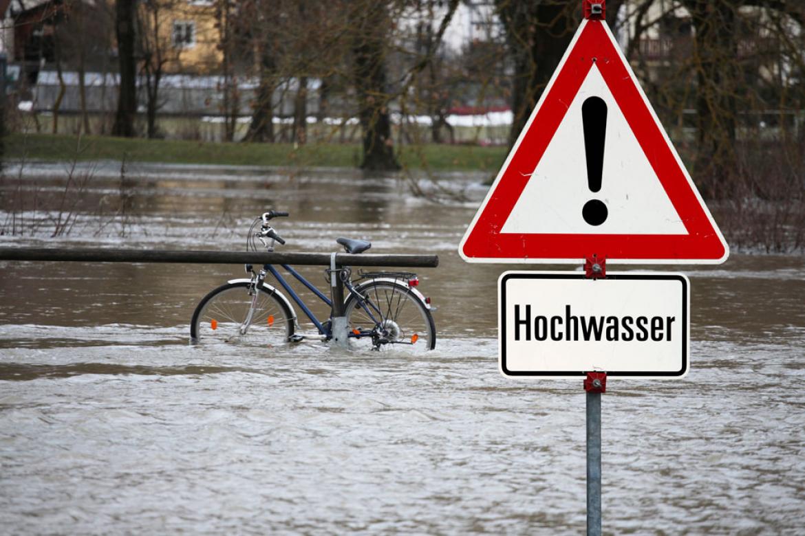 Überflutete Landschaft mit Fahrrad an Geländer angekettet zu Artikel: Ihre Möglichkeiten bei in Hochwassergebiet geplantem Urlaub