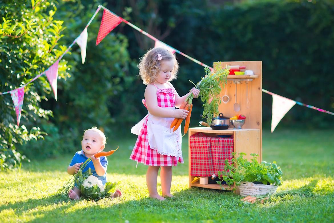 Kinder in Garten mit Spielküche und Karotten, Kita auf Esspedition