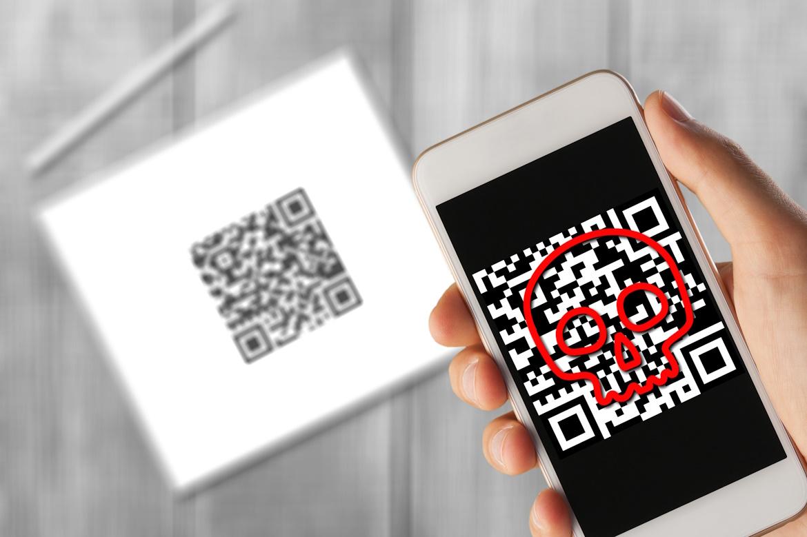 Hintergrund: Tablet mit QR-Code, vorne von Smartphone gescannter QR-Code mit rotem Totenkopf