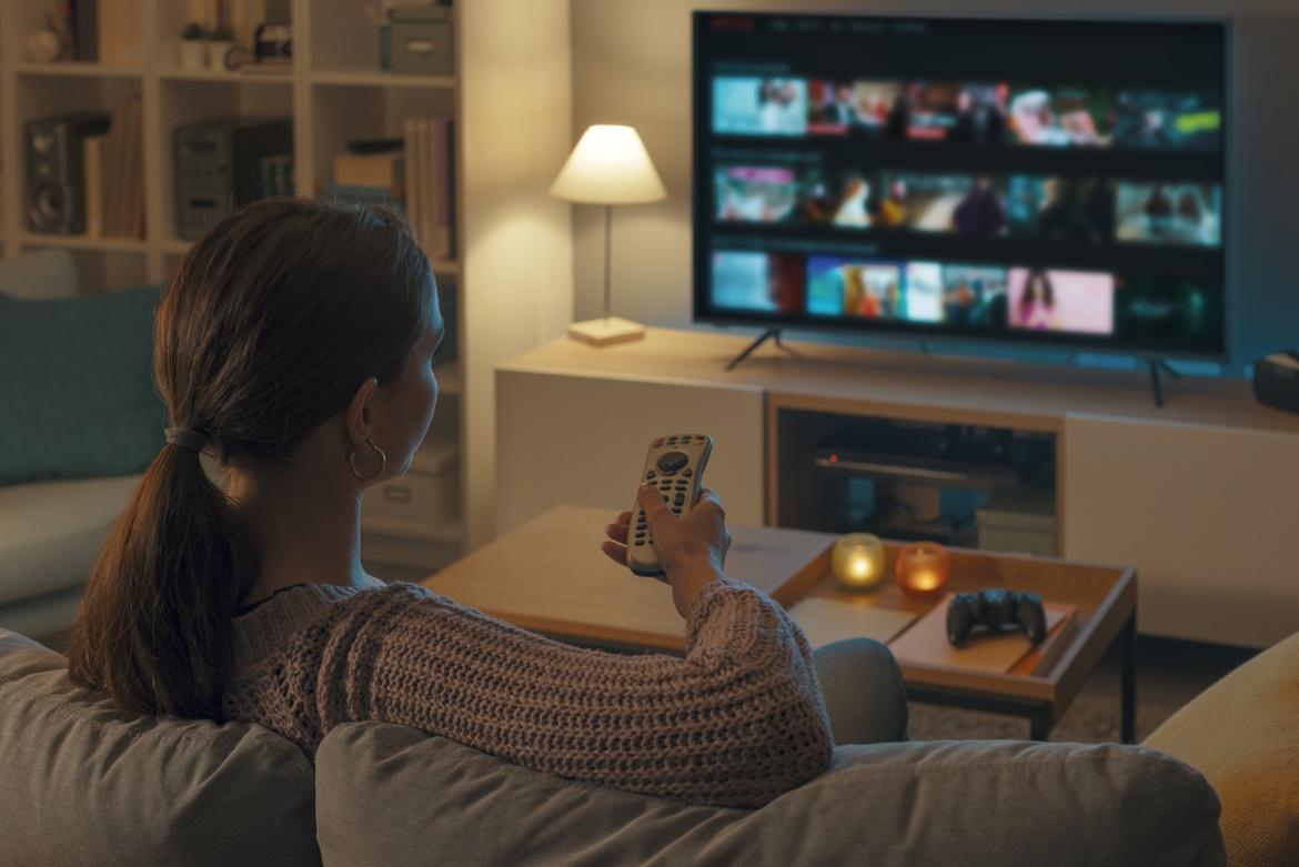 Schmuckbild: Frau sitzt auf Sofa, entspannt, schaut Fernsehen