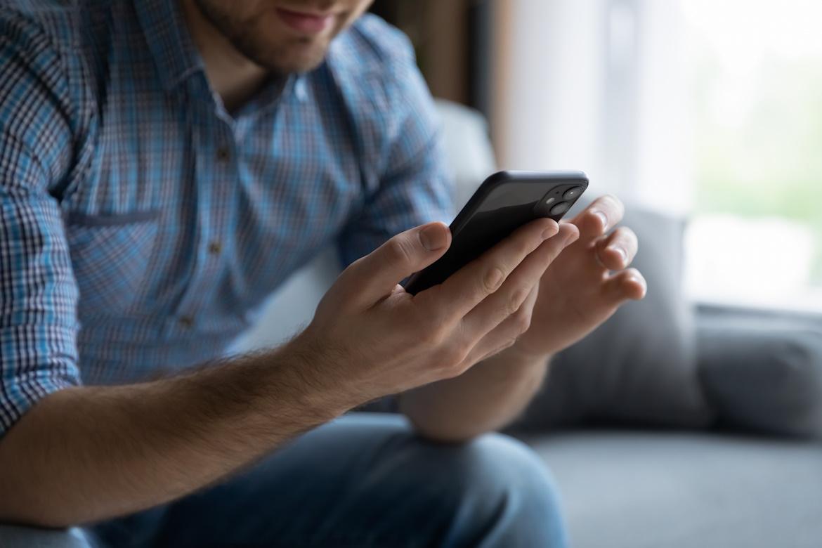 Mann auf Sofa mit Smartphone in der Hand