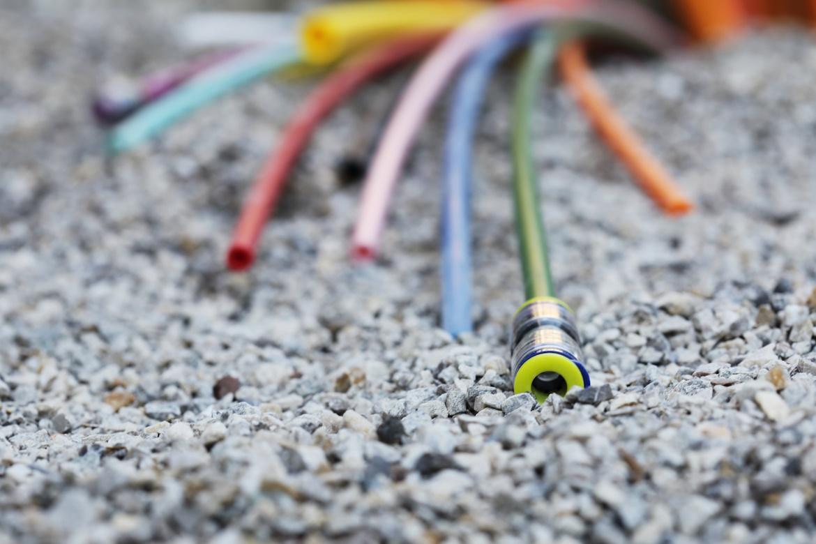 Verschieden bunte Kabel auf Schotter, Glasfaser