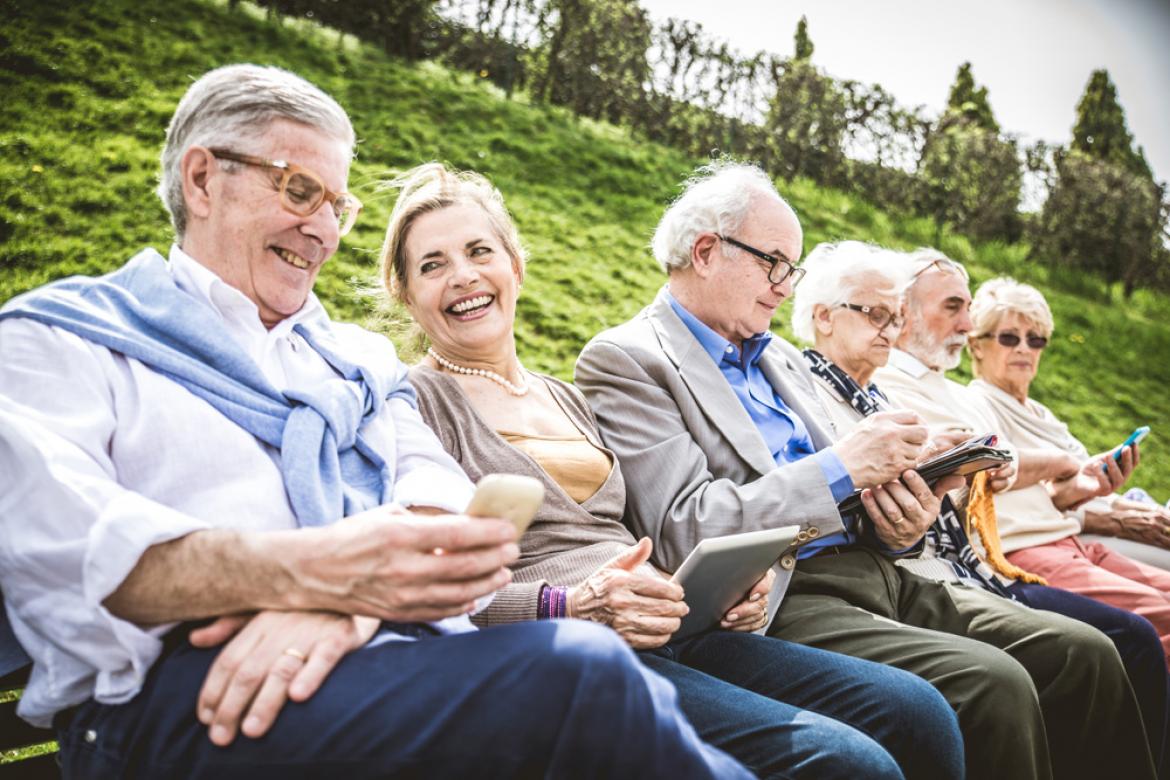 Mehrere Senioren auf Bank mit Smartphones