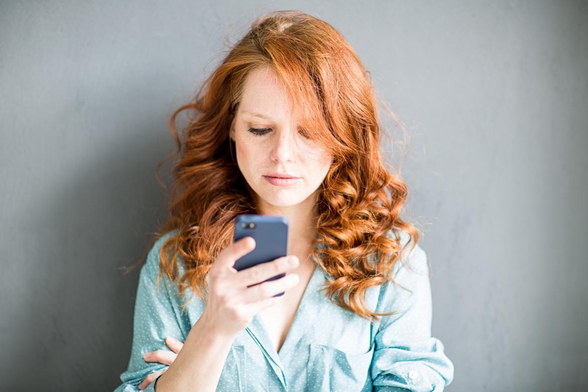 Frau hält Smartphon in der Hand und schaut es mit fragendem Blick an