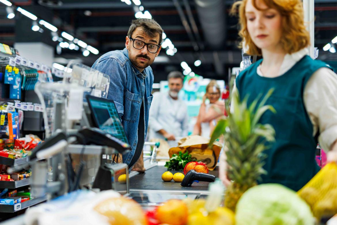 Mann an der Supermarktkasse wundert sich über den Preis