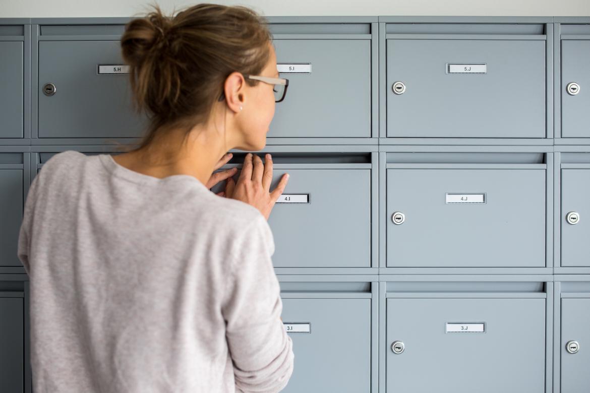 Nachsendeauftrag Frau schaut in Briefkasten