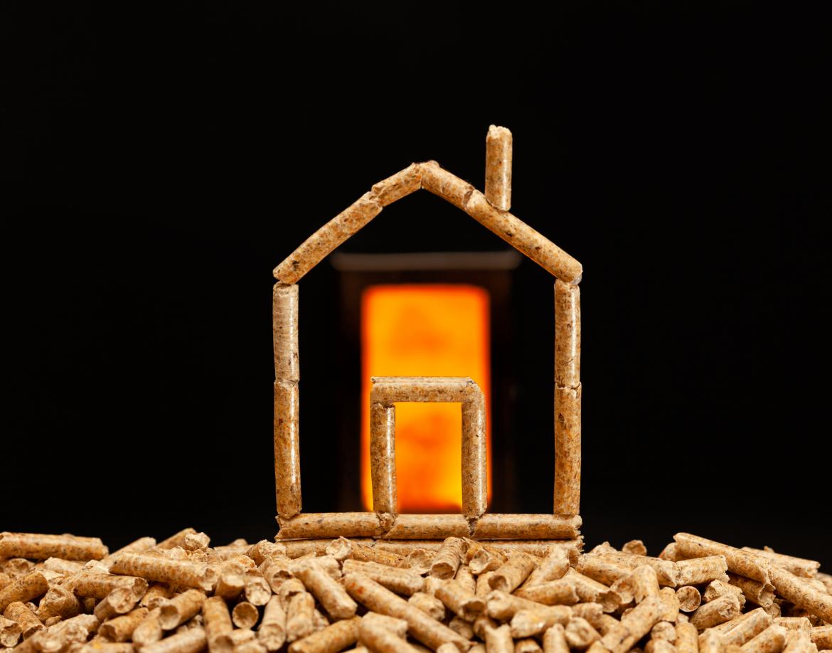 Haus aus Pellets auf schwarzem Hintergrund mit loderndem Feuer in der Mitte