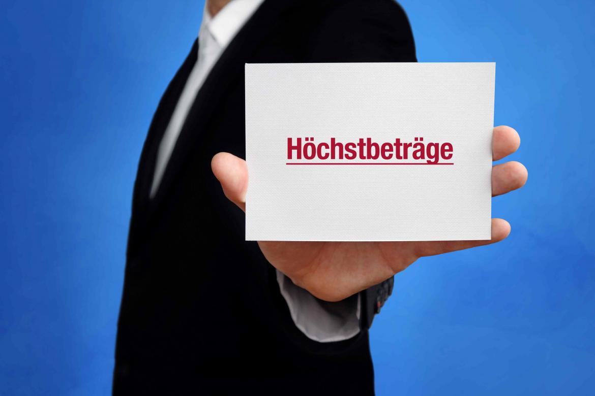 MAnn im Anzug hält Schild mit Höchstbeträge in der Hand.