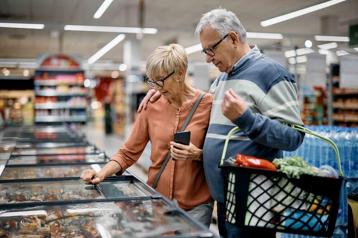 Zwei ältere Menschen stehen im Supermarkt vor der Gefriertruhe