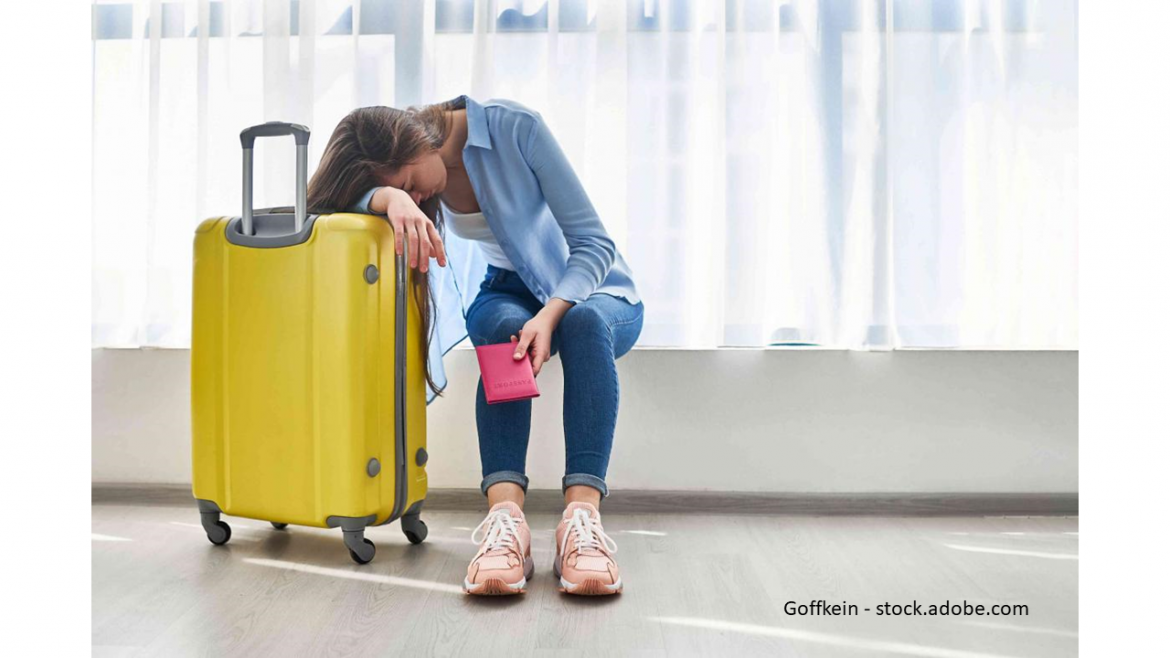 Frau stützt sich am Flughafen auf gelben Koffer Flug ist verspätet