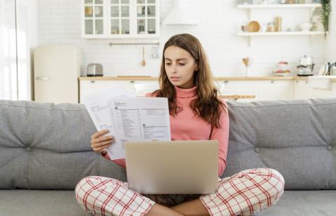 Frau auf Sofa mit Laptop und Brief zu Inkassoforderung EOS